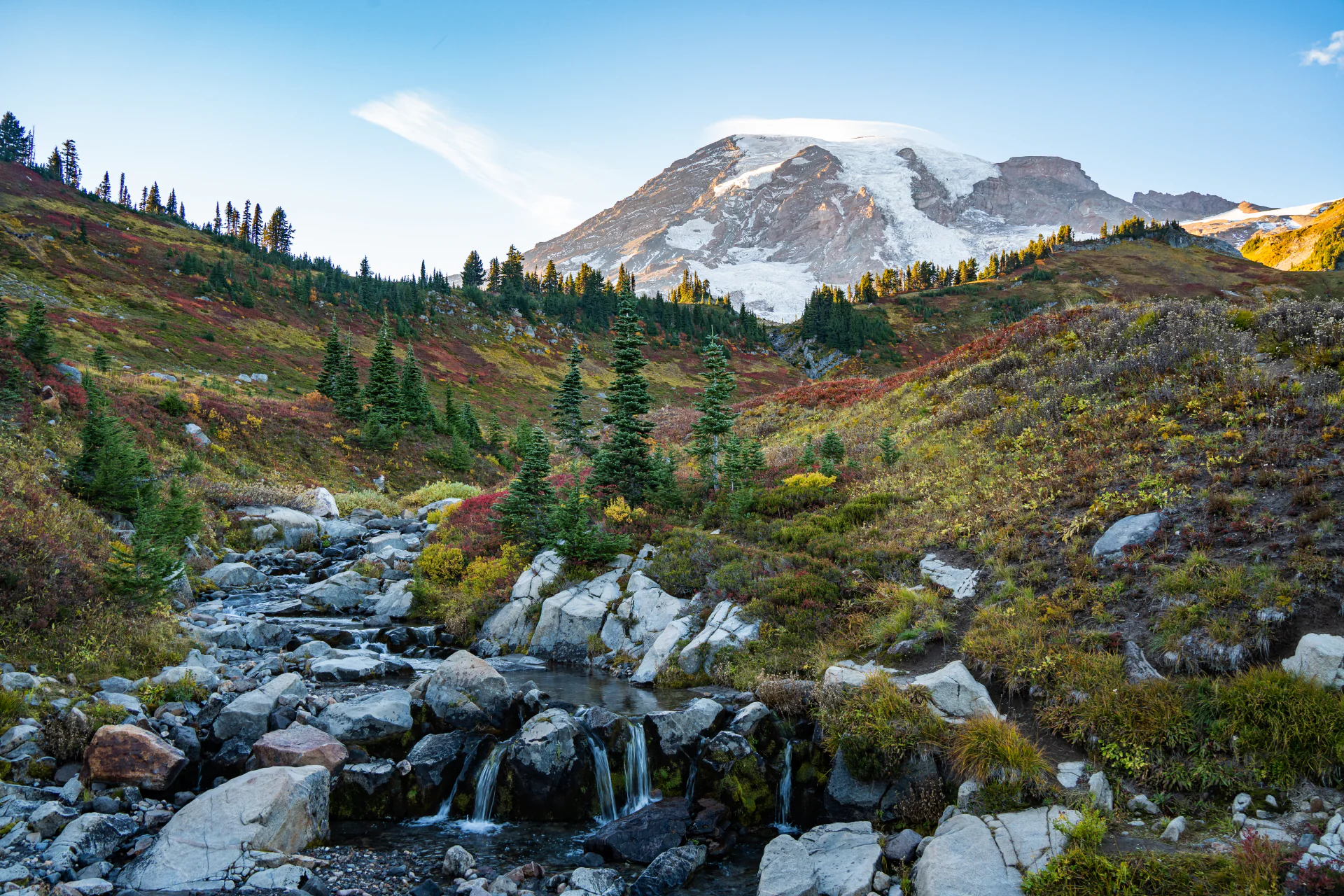 Mount Rainier above a waterfall, evergreens, and autumn meadows